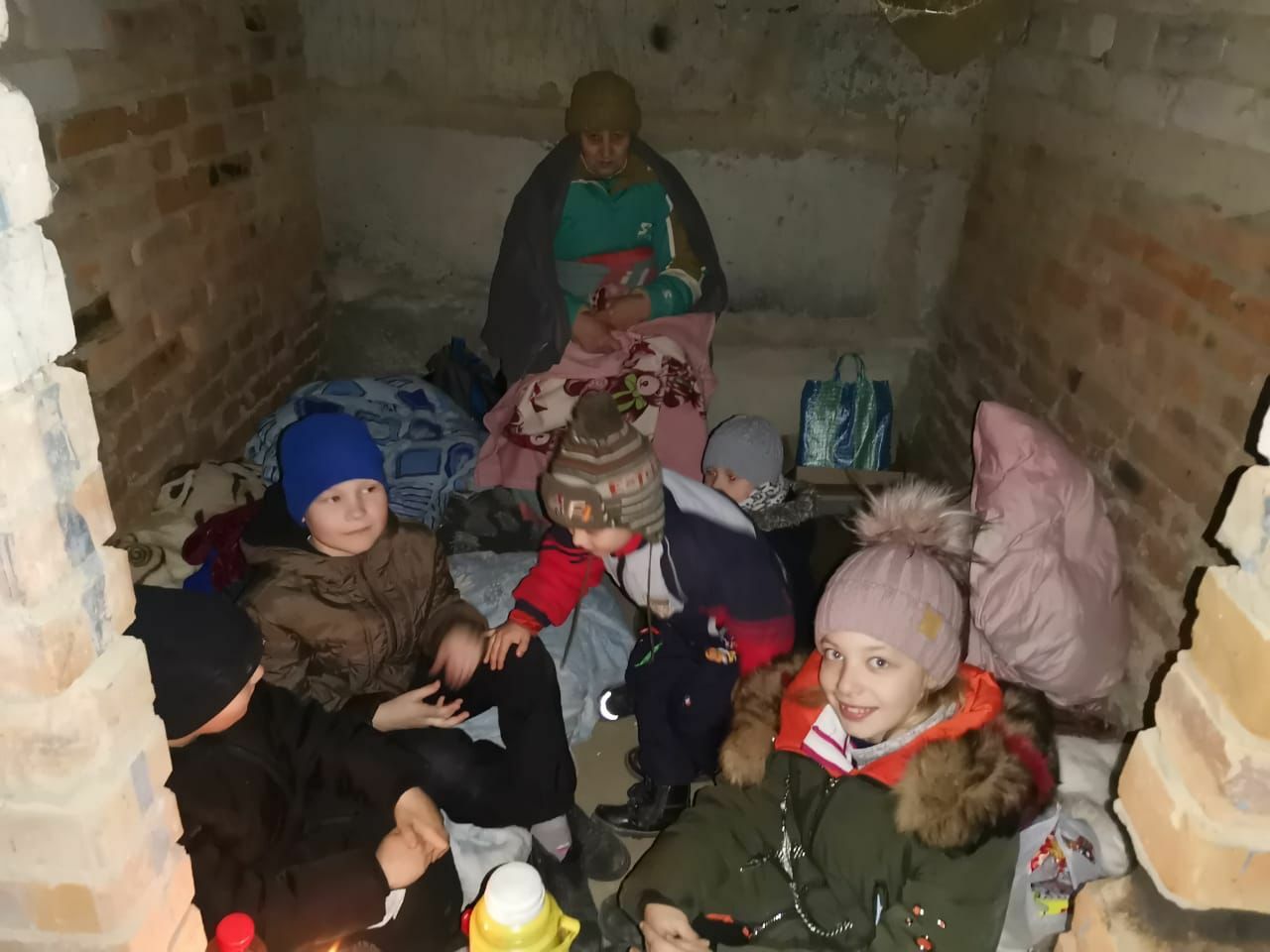 A family of Believers sheltering inside a basement for protection from the cold and missile attacks.